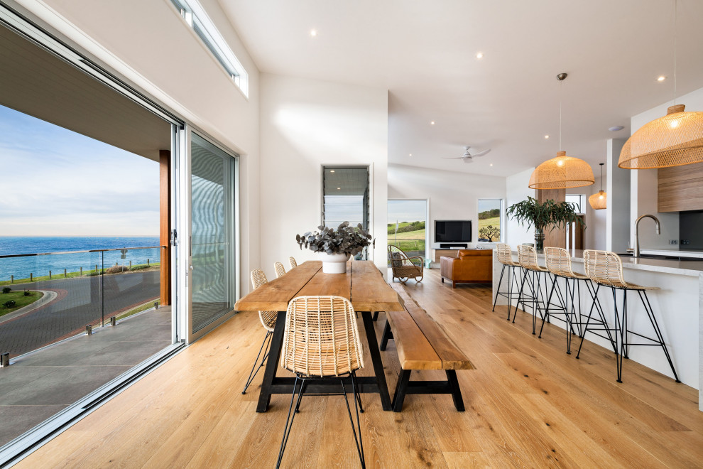 Idee per una sala da pranzo aperta verso il soggiorno stile marino di medie dimensioni con pareti bianche, pavimento in legno massello medio e pavimento marrone