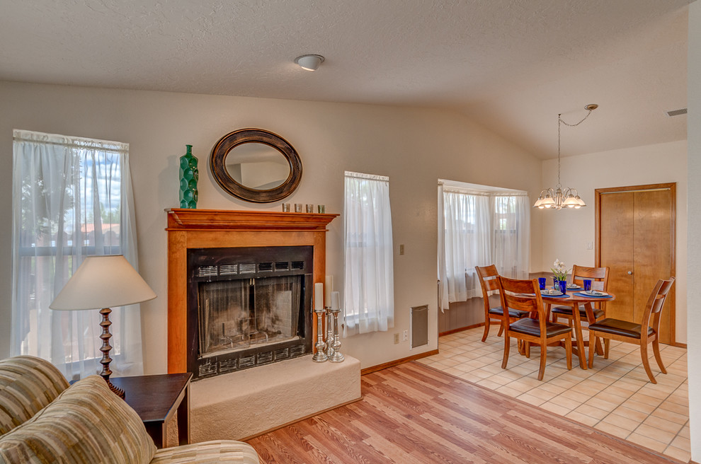 This is an example of a small classic open plan dining room in Albuquerque with white walls, ceramic flooring, a standard fireplace and a wooden fireplace surround.