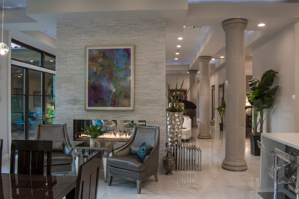 Esempio di una grande sala da pranzo aperta verso la cucina design con pareti bianche, pavimento in marmo, camino bifacciale e cornice del camino in pietra