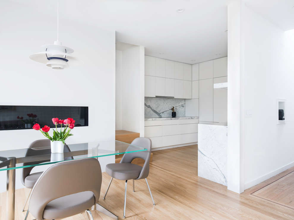 Стильный дизайн: кухня-столовая в стиле модернизм с белыми стенами, светлым паркетным полом и горизонтальным камином - последний тренд
