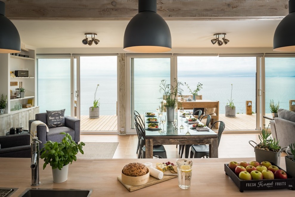 Idées déco pour une salle à manger ouverte sur la cuisine bord de mer de taille moyenne avec un mur blanc, un sol en bois brun, un sol beige et éclairage.