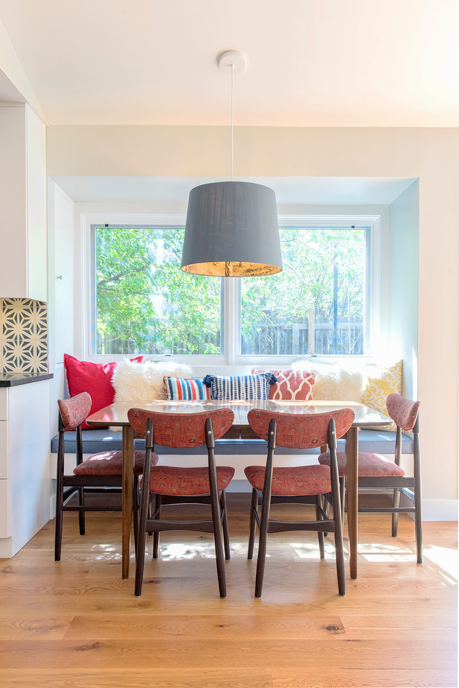 This is an example of a midcentury dining room in Denver with yellow walls, medium hardwood flooring and brown floors.