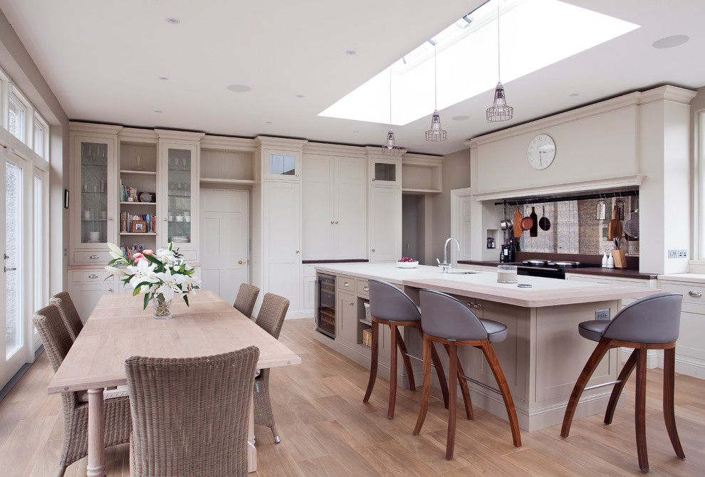 Cette photo montre une salle à manger ouverte sur la cuisine nature avec parquet clair, un mur gris et aucune cheminée.