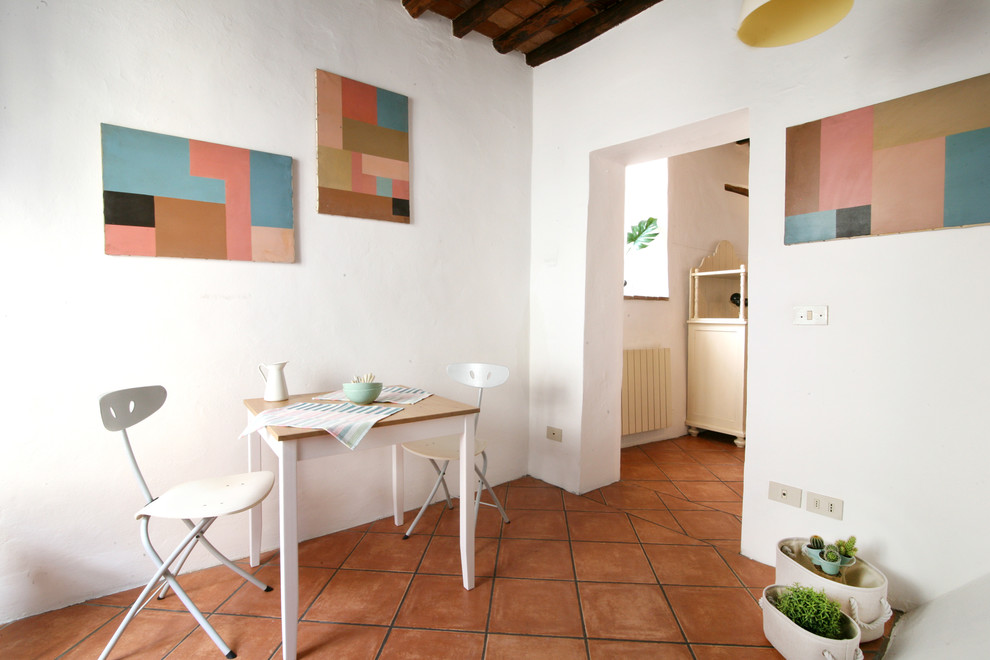 На фото: столовая в средиземноморском стиле с белыми стенами, полом из терракотовой плитки и оранжевым полом с