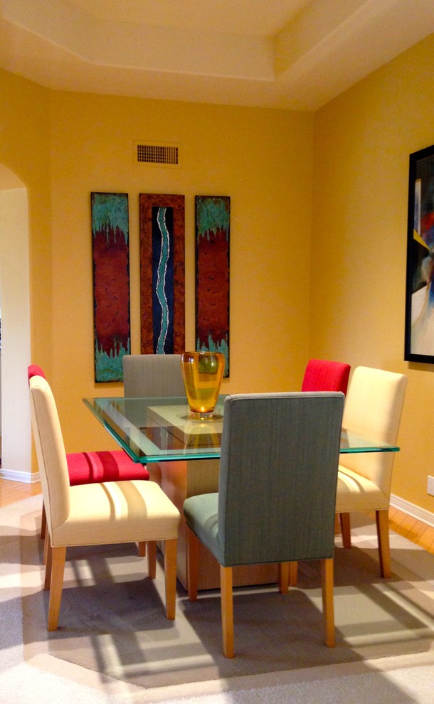 Ispirazione per una piccola sala da pranzo aperta verso la cucina design con pareti gialle, parquet chiaro, camino classico e cornice del camino piastrellata