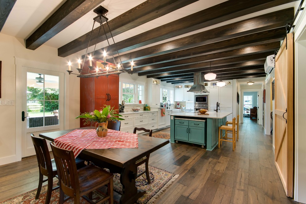 Immagine di una sala da pranzo aperta verso la cucina country con pareti beige, parquet scuro e pavimento marrone