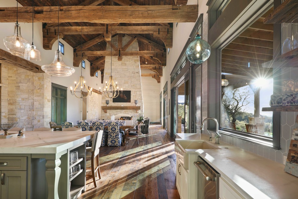 Geräumige Rustikale Wohnküche mit beiger Wandfarbe, braunem Holzboden, Tunnelkamin, Kaminumrandung aus Stein und braunem Boden in Austin