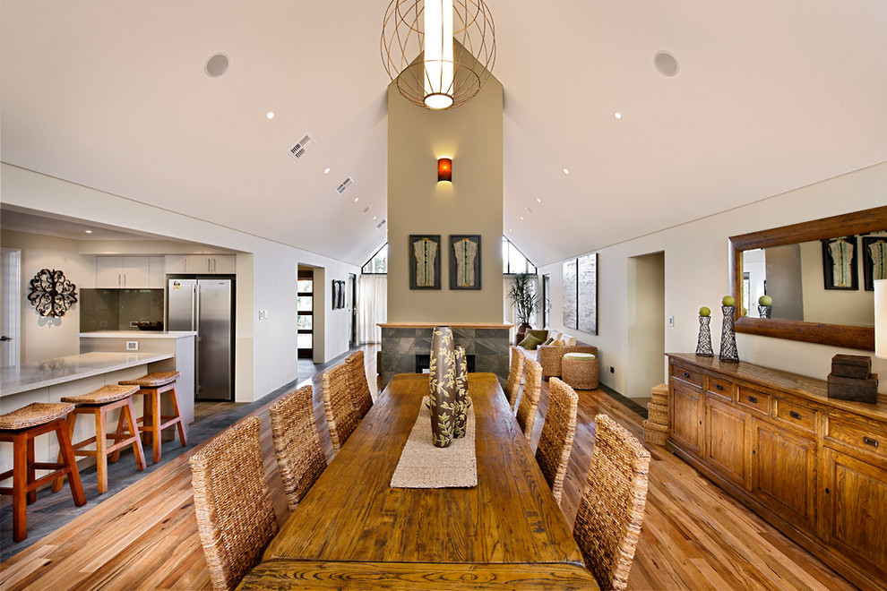 Cette image montre une grande salle à manger ouverte sur la cuisine rustique avec un mur beige, un sol en vinyl, une cheminée double-face et un manteau de cheminée en pierre.