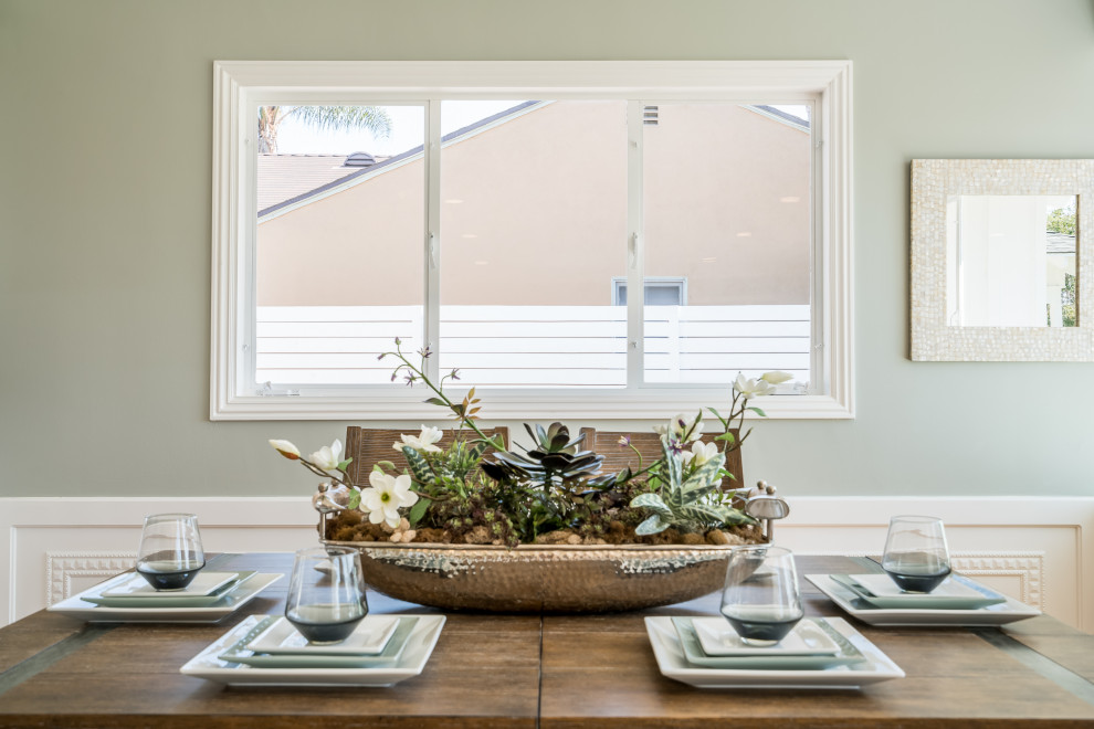 Cette photo montre une salle à manger ouverte sur le salon nature de taille moyenne avec un mur vert, un sol en bois brun, une cheminée standard, un manteau de cheminée en brique et boiseries.