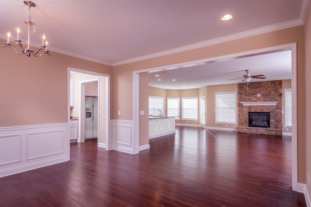 Cette image montre une salle à manger ouverte sur la cuisine traditionnelle avec un mur beige, parquet foncé, une cheminée standard et un manteau de cheminée en pierre.