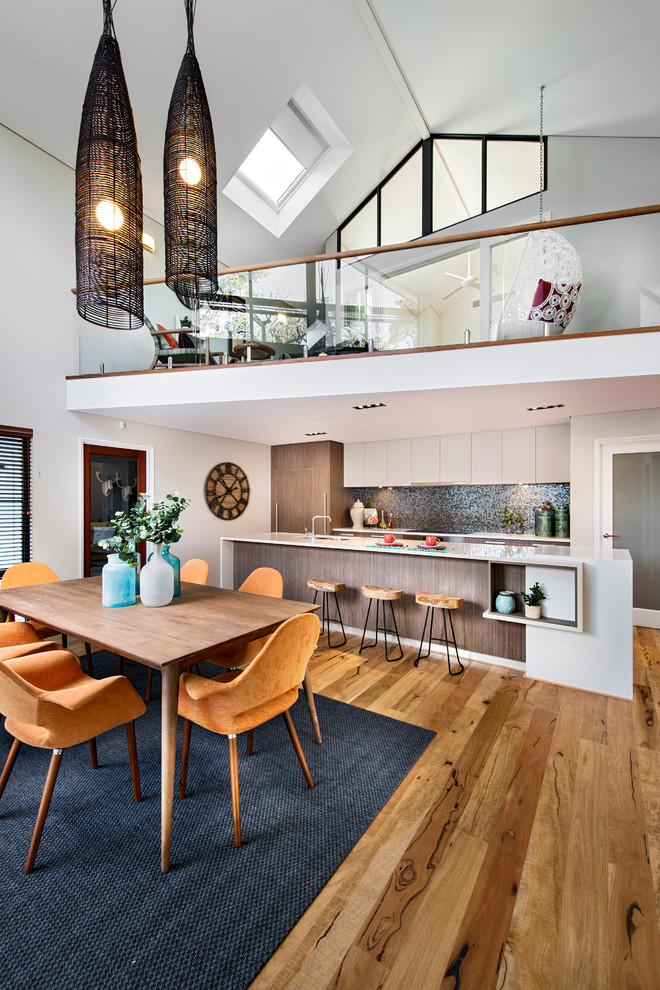 Cette image montre une salle à manger ouverte sur la cuisine design avec un mur blanc, un sol en bois brun et aucune cheminée.