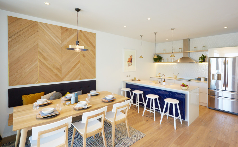 Foto di una sala da pranzo aperta verso la cucina nordica con pareti bianche e pavimento in legno massello medio