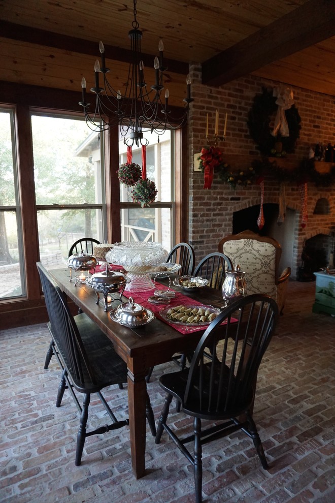 Cette image montre une salle à manger ouverte sur la cuisine rustique de taille moyenne avec un mur multicolore, un sol en brique, un poêle à bois et un manteau de cheminée en brique.