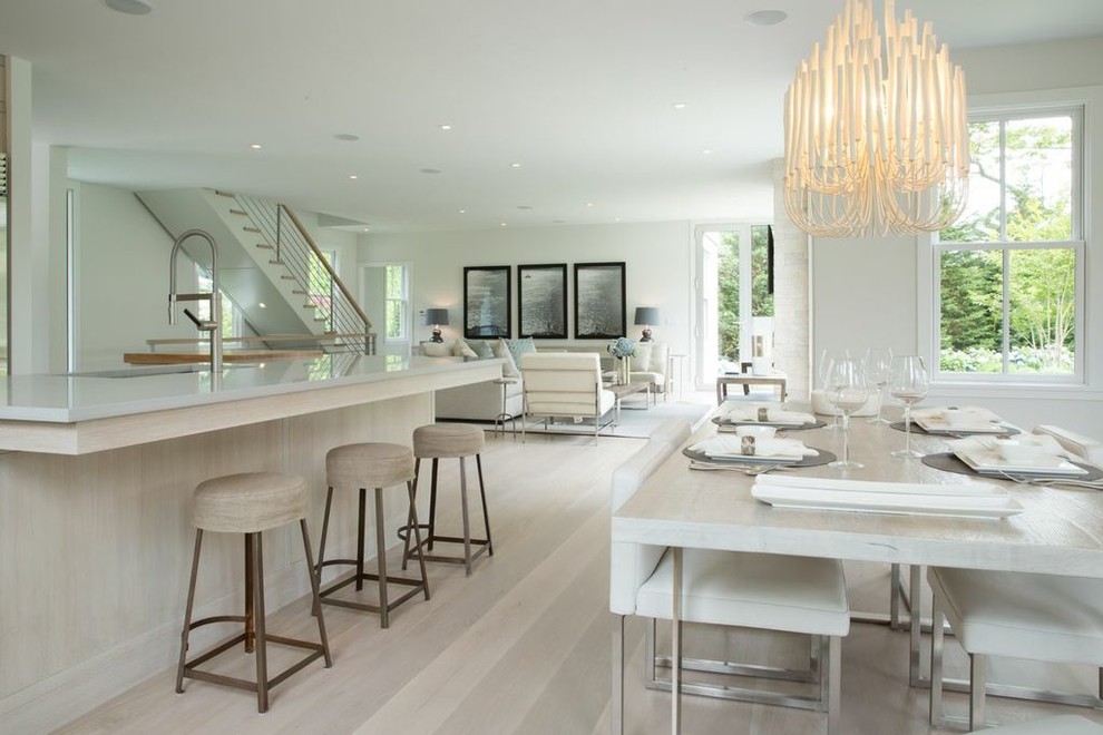 Cette image montre une salle à manger ouverte sur le salon design avec un mur blanc, parquet clair et éclairage.