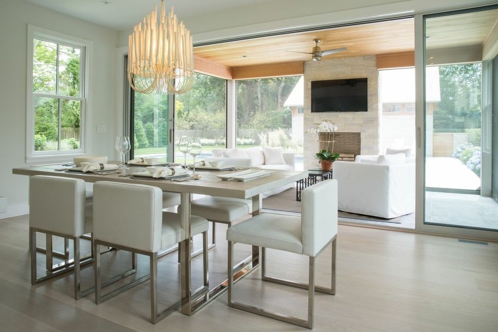 This is an example of a contemporary dining room in New York with white walls and light hardwood flooring.