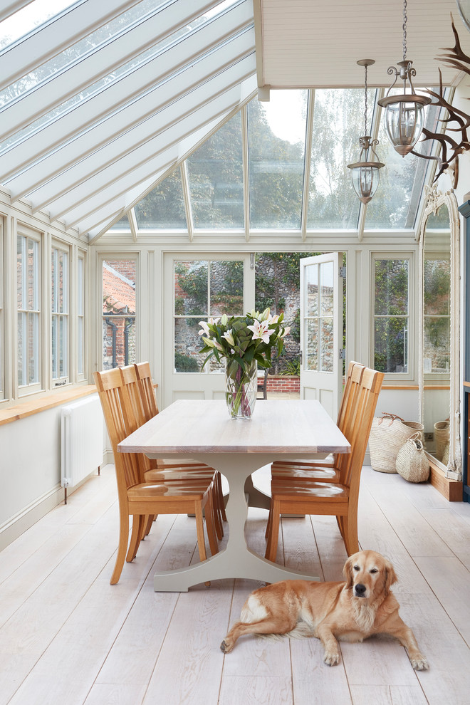 This is an example of a large country conservatory in Other with light hardwood flooring.