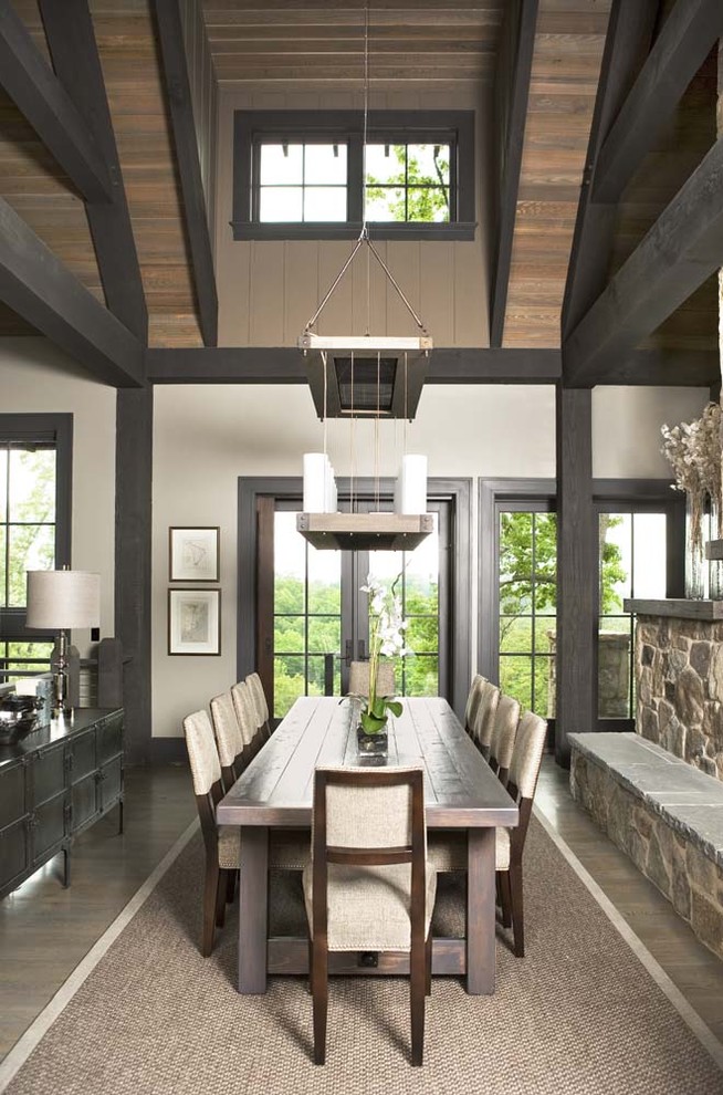 Inspiration for a large rustic open plan dining room in Other with white walls, light hardwood flooring, a two-sided fireplace, a stone fireplace surround and feature lighting.