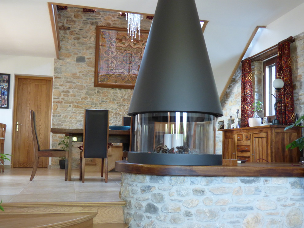 他の地域にある高級な中くらいなラスティックスタイルのおしゃれなダイニングキッチン (ベージュの壁、セラミックタイルの床、木材の暖炉まわり、吊り下げ式暖炉) の写真