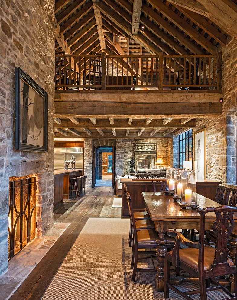 Immagine di una sala da pranzo aperta verso il soggiorno stile rurale con parquet scuro, camino classico, cornice del camino in pietra e pavimento marrone