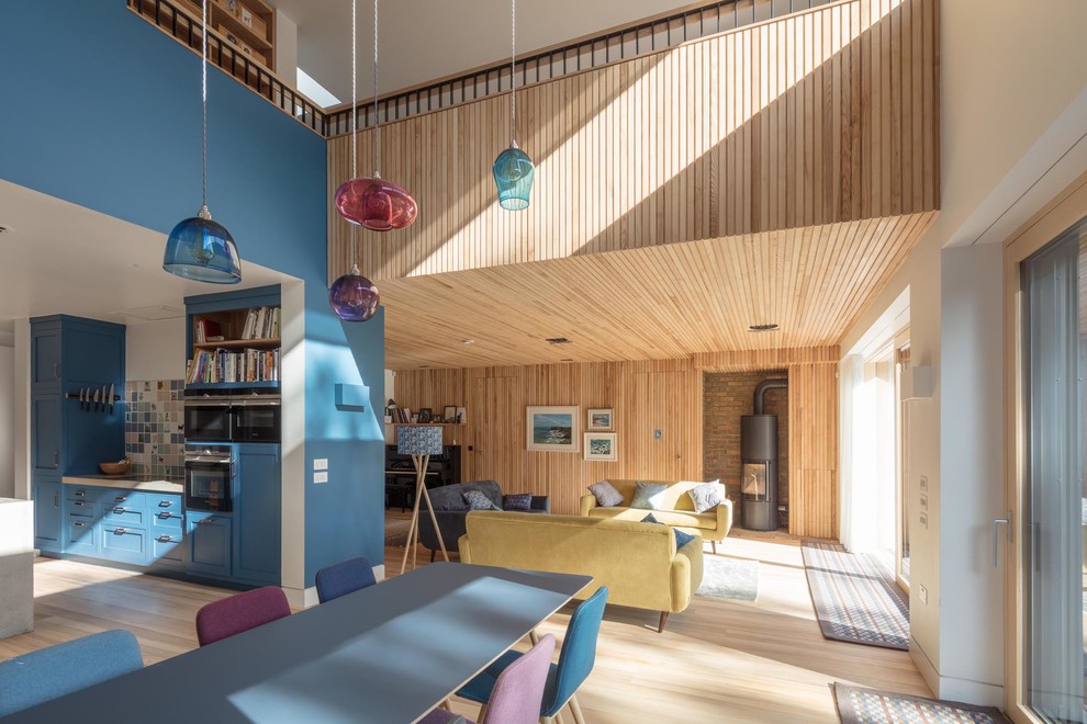 Ispirazione per una sala da pranzo minimal di medie dimensioni e chiusa con pareti blu, parquet chiaro, cornice del camino in mattoni, pavimento beige e stufa a legna