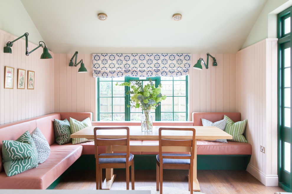Foto de comedor tradicional renovado sin chimenea con con oficina, paredes rosas, suelo de madera en tonos medios, suelo marrón y panelado
