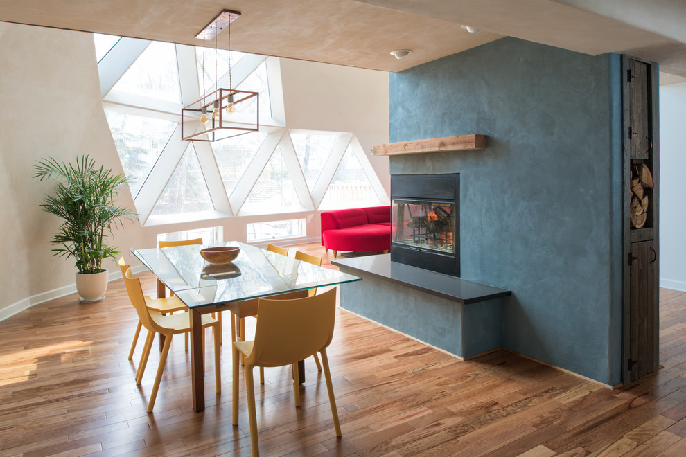 Imagen de comedor actual extra grande abierto con paredes azules, suelo de bambú y marco de chimenea de metal