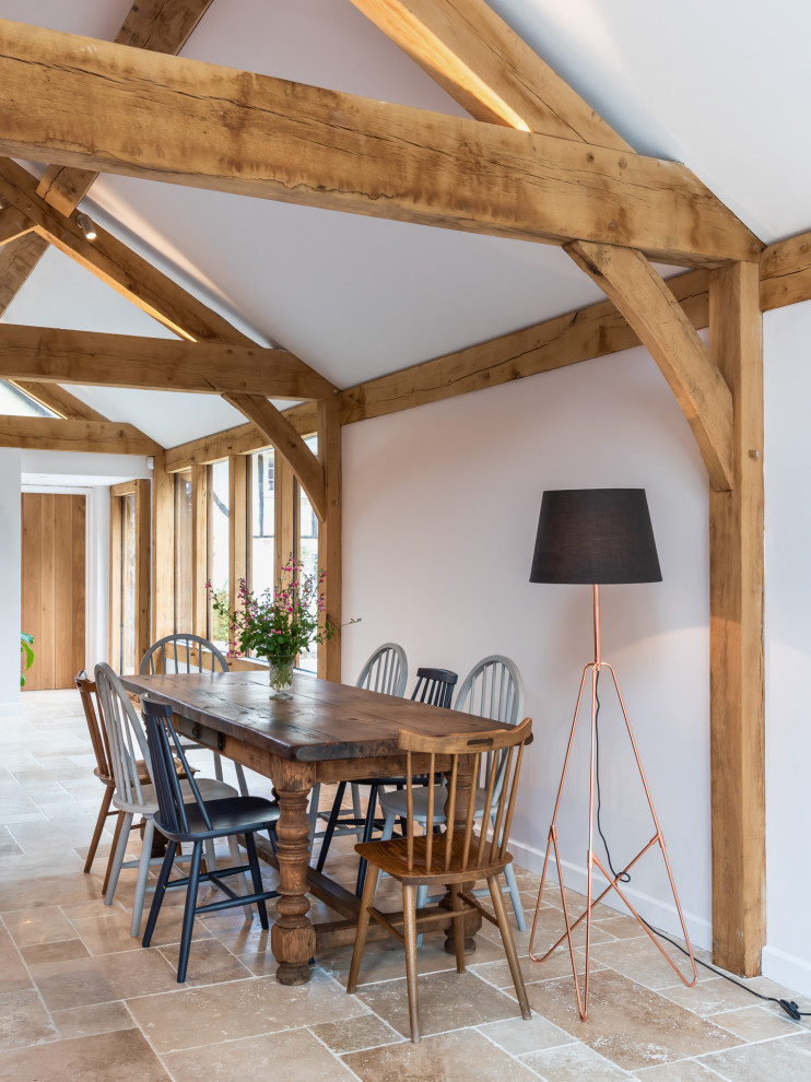 Idee per una sala da pranzo aperta verso il soggiorno country con pareti bianche, pavimento beige e travi a vista