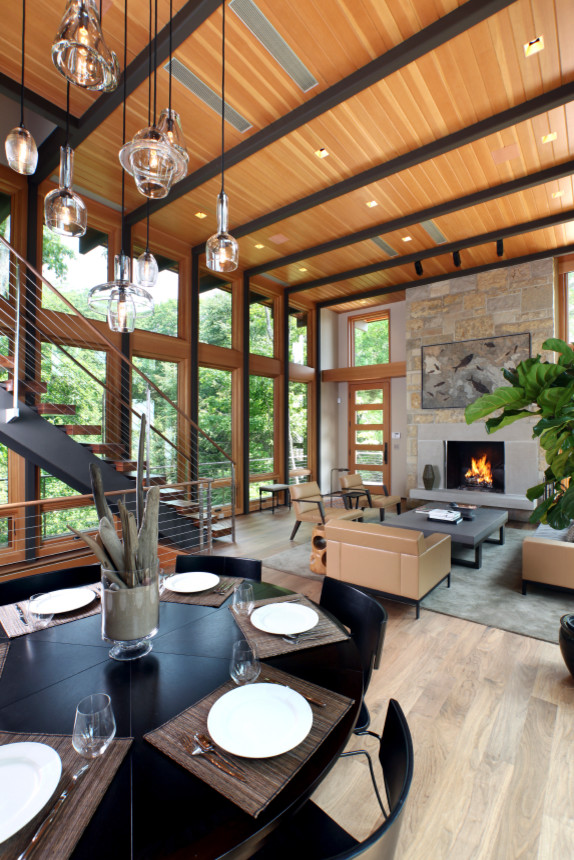Large contemporary open plan dining room in Grand Rapids with beige walls, light hardwood flooring, a standard fireplace and a stone fireplace surround.