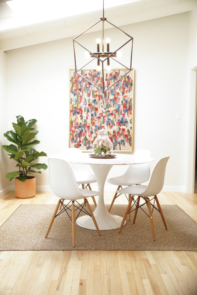 Example of a trendy light wood floor enclosed dining room design in Los Angeles with white walls