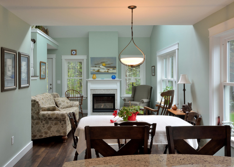 Immagine di una piccola sala da pranzo aperta verso la cucina chic con pareti blu, parquet scuro e camino classico