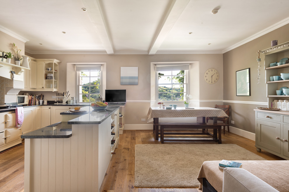 Große Country Wohnküche mit beiger Wandfarbe und braunem Holzboden in Devon