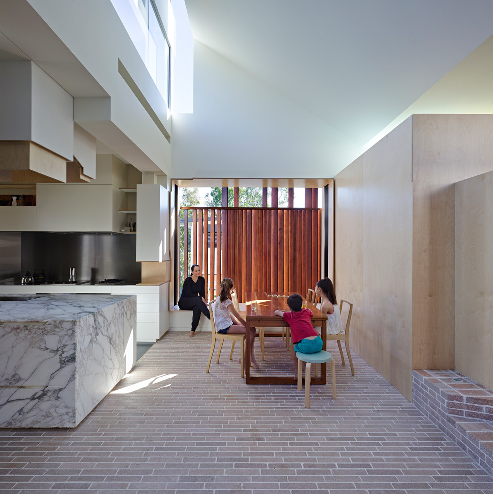 Aménagement d'une salle à manger contemporaine avec un sol en brique et un mur marron.