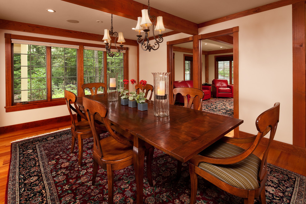 Cette image montre une grande salle à manger traditionnelle fermée avec un mur blanc, un sol en bois brun et aucune cheminée.