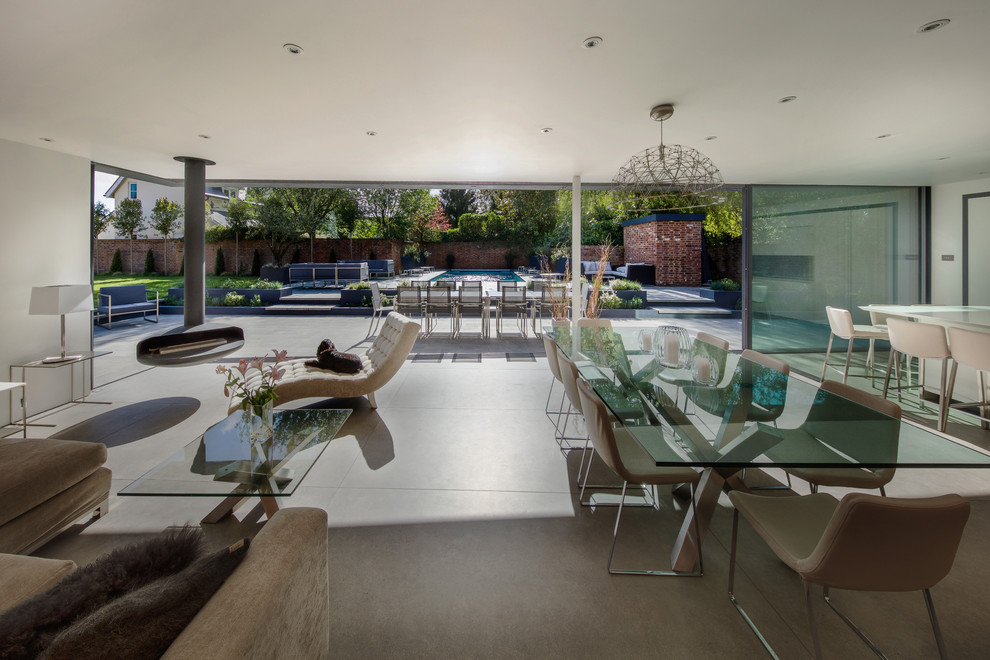 Стильный дизайн: большая гостиная-столовая в стиле модернизм с белыми стенами, бетонным полом, подвесным камином и серым полом - последний тренд