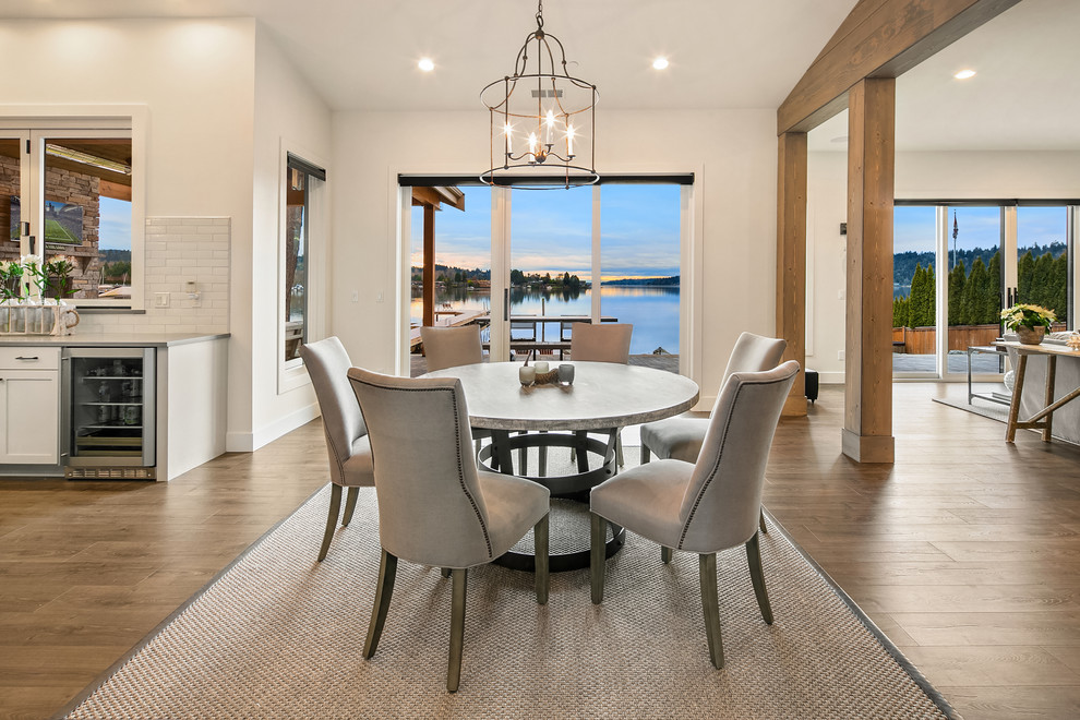 Immagine di una sala da pranzo aperta verso il soggiorno stile marino con pareti bianche e pavimento in legno massello medio