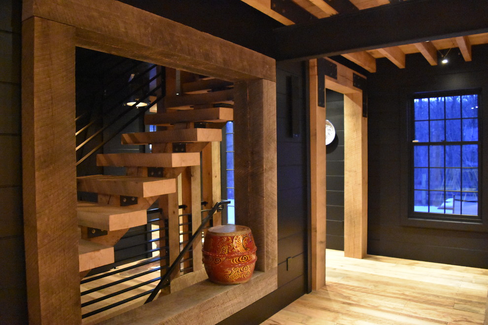 Cette image montre une salle à manger ouverte sur la cuisine urbaine avec un mur noir, un sol en bois brun, une cheminée double-face et un manteau de cheminée en béton.