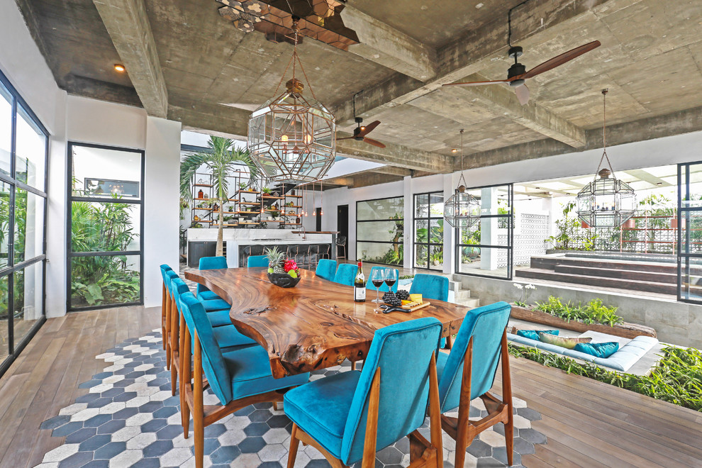 Foto di una sala da pranzo aperta verso il soggiorno tropicale con pareti bianche e pavimento marrone