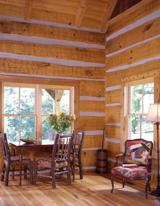 Cette image montre une petite salle à manger ouverte sur la cuisine chalet avec un mur marron et parquet clair.