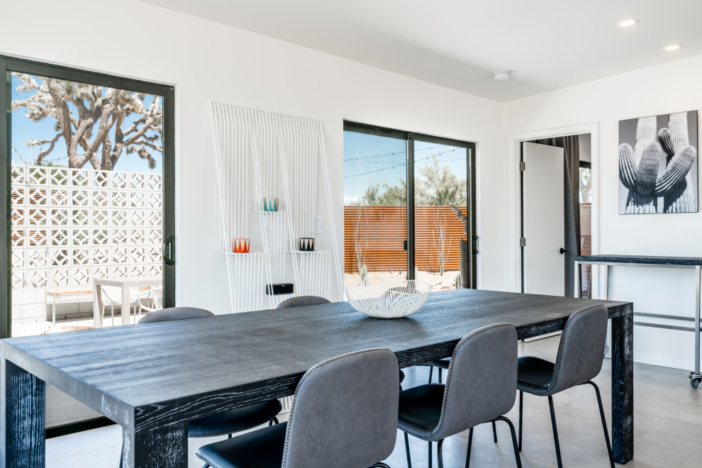 Cette image montre une salle à manger ouverte sur le salon minimaliste de taille moyenne avec un mur blanc, sol en béton ciré, une cheminée ribbon, un manteau de cheminée en bois et un sol gris.