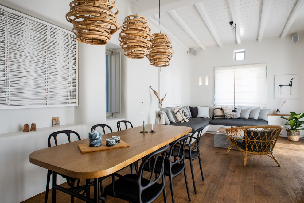 Idée de décoration pour une salle à manger ouverte sur le salon méditerranéenne avec un mur blanc, un sol en bois brun et un sol marron.