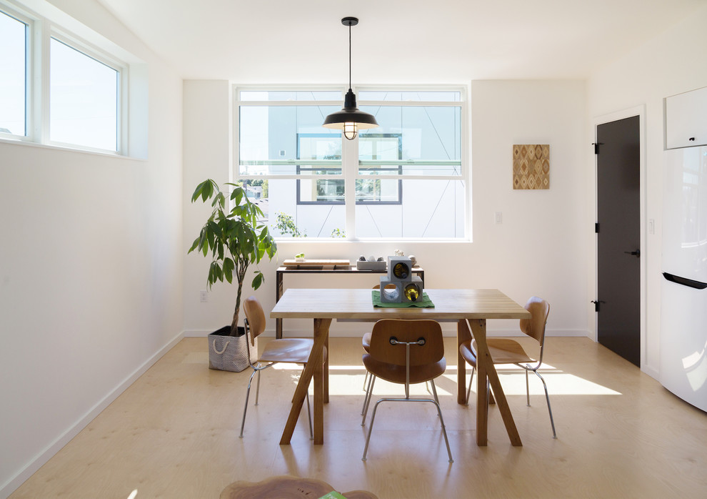 Foto di una piccola sala da pranzo aperta verso il soggiorno minimal con pareti bianche, pavimento in compensato e pavimento giallo