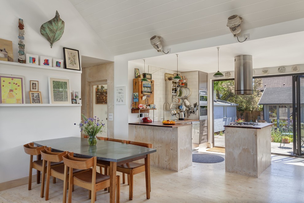 Foto di una sala da pranzo aperta verso la cucina stile marino con pareti bianche, pavimento in compensato e pavimento beige