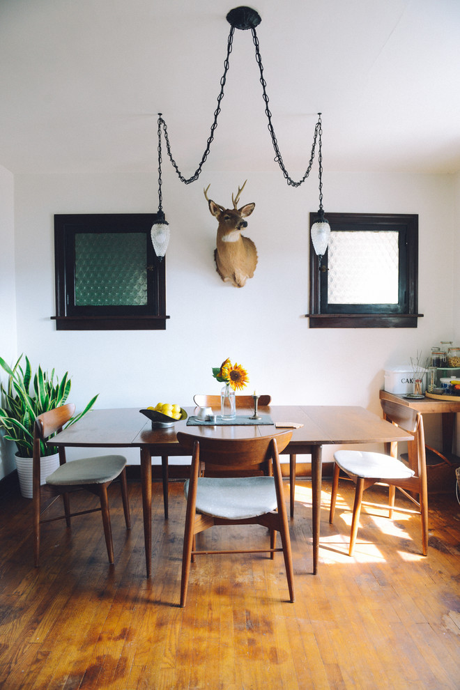 Exemple d'une salle à manger éclectique de taille moyenne avec un mur blanc et un sol en bois brun.