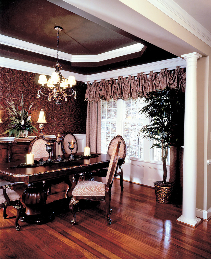 Immagine di una sala da pranzo aperta verso il soggiorno classica di medie dimensioni con pareti marroni, pavimento in legno massello medio e nessun camino