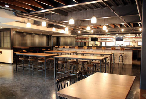 Aménagement d'une très grande salle à manger ouverte sur la cuisine industrielle avec un mur gris et sol en béton ciré.