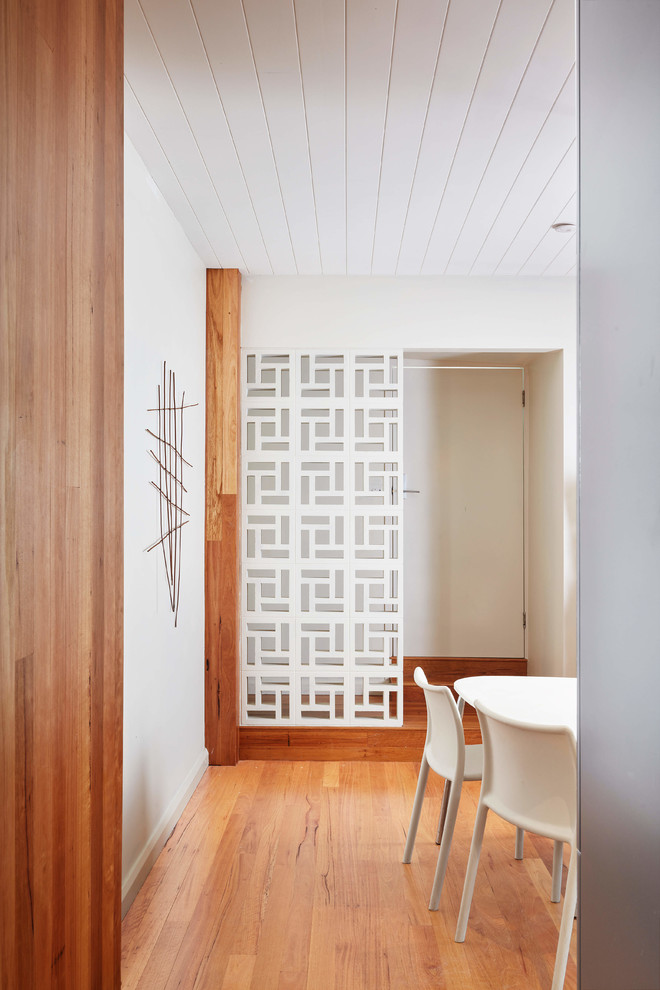 Idée de décoration pour une petite salle à manger ouverte sur le salon vintage avec un mur blanc, un sol en bois brun et un sol marron.