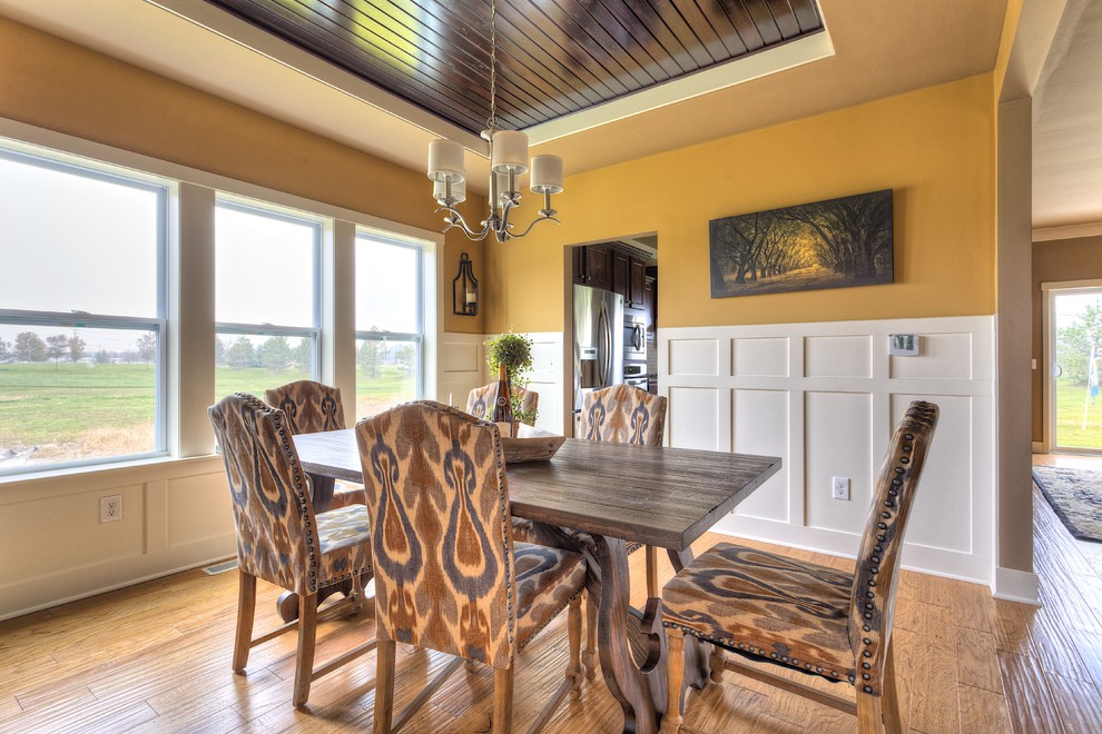 Idée de décoration pour une salle à manger craftsman fermée avec un mur jaune et un sol en bois brun.