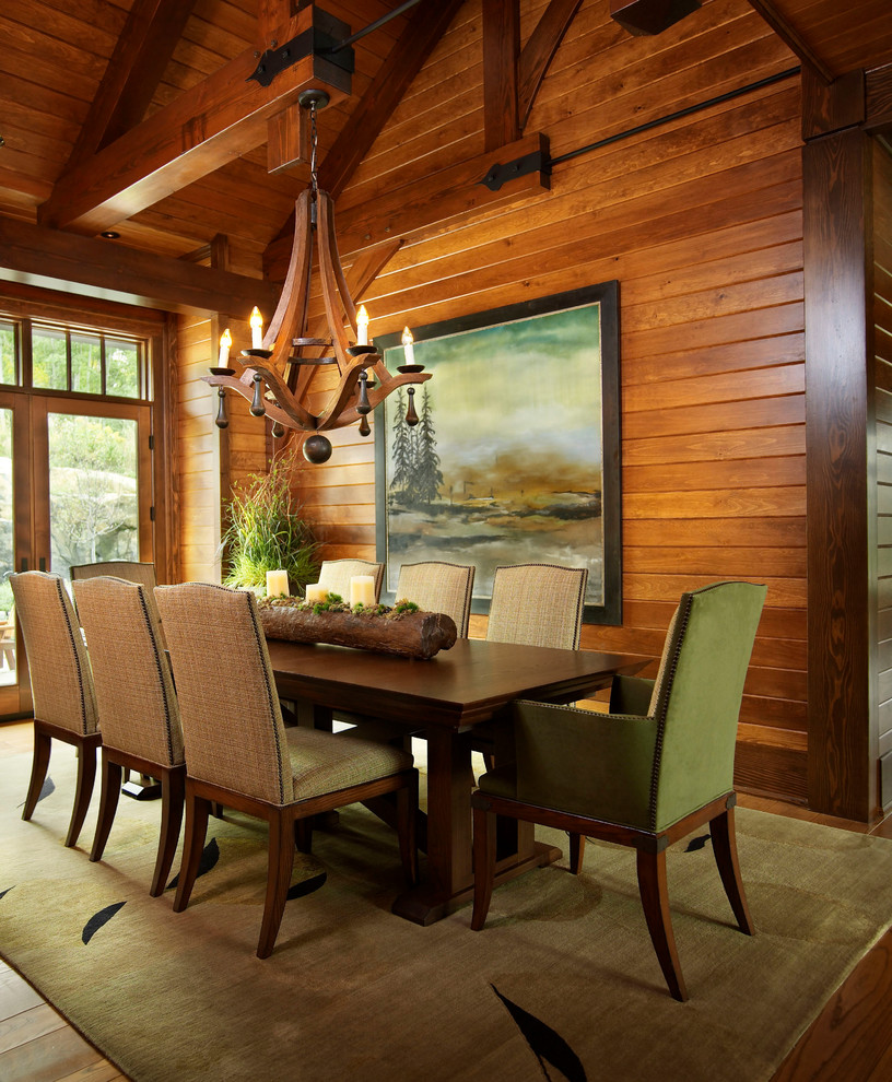 Cette image montre une très grande salle à manger ouverte sur la cuisine chalet avec un mur marron, un sol en bois brun et un sol marron.