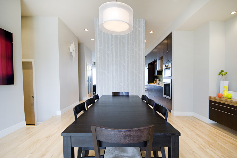 Foto di una sala da pranzo aperta verso la cucina minimal con pareti grigie e parquet chiaro