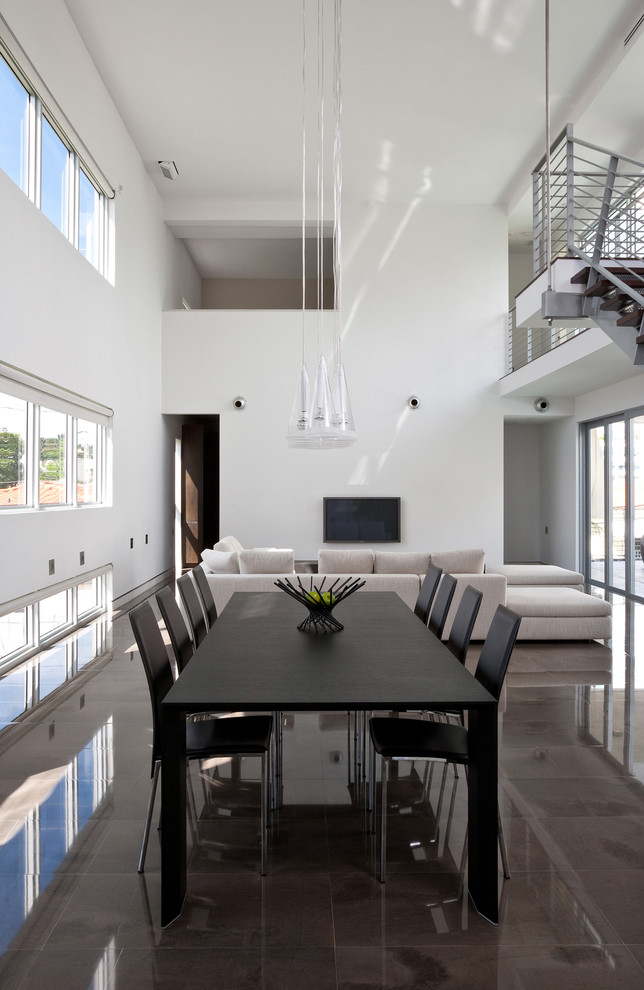 Réalisation d'une grande salle à manger ouverte sur le salon minimaliste avec un mur blanc et sol en béton ciré.